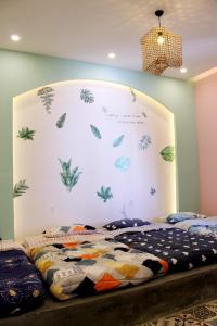 una camera da letto con una parete con foglie dipinte sopra di WIN Homestay a Quy Nhon