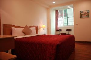 白河區的住宿－麗湯溫泉渡假山莊 ，一间卧室配有一张带红色毯子的床和窗户。