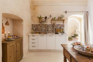 a kitchen with white cabinets and a counter with fruits on it at Angolo del poeta suite in Matera