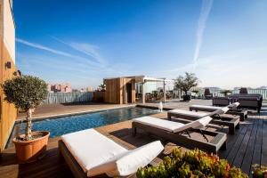 eine Dachterrasse mit Stühlen und einem Pool auf einem Gebäude in der Unterkunft Hotel Urpí in Sabadell