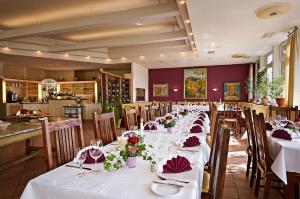une salle à manger avec des tables blanches, des chaises et des fleurs dans l'établissement EUT-IN Hotel Alte Straßenmeisterei, à Eutin