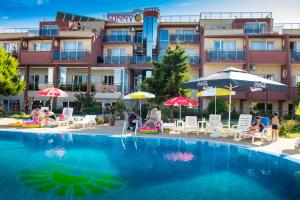 a swimming pool in front of a hotel with chairs and umbrellas at Hotel Sunny in Sozopol