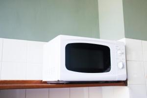 a white microwave sitting on a shelf in a kitchen at Amsterdam Hostel Annemarie in Amsterdam