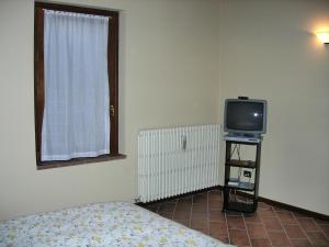 - une chambre avec un lit et une petite télévision dans l'établissement Agriturismo Campass, à Castelvetro Piacentino