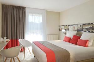 una habitación de hotel con una cama grande con almohadas rojas en Best Western Les Bains Hotel et SPA, en Perros-Guirec