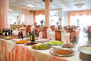 a banquet hall with tables with food and bottles of wine at Hotel Fortuna in San Bartolomeo al Mare +18 photos