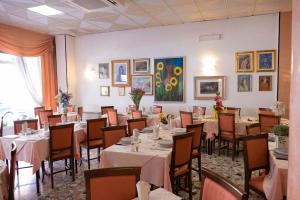 a dining room with tables and chairs and paintings on the wall at Hotel Fortuna in San Bartolomeo al Mare