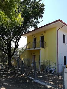 une maison jaune avec un arbre et une clôture dans l'établissement VillaOlivara, à Pizzo