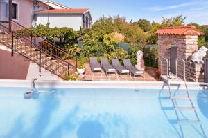 basen z leżakami obok domu w obiekcie Apartment Edo 1755 w mieście Peresiji
