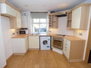 a kitchen with white cabinets and a washing machine at Drovers Cottage in Hayfield