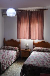 1 dormitorio con 2 camas y mesa con lámpara en Hostal Santa Ana, en San José de La Rinconada