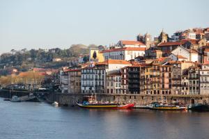 a group of boats in a river with buildings at The House of Sandeman - Hostel & Suites in Vila Nova de Gaia