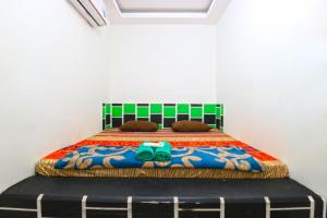 een slaapkamer met een bed met een kleurrijke deken bij Habibah Syariah Hotel in Jakarta