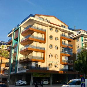 budynek z balkonami i samochody zaparkowane przed nim w obiekcie Cozy apartment Centr Alanya w mieście Alanya