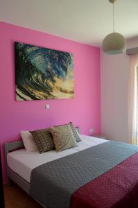 リメナリアにあるEva Apartmentsのピンクの壁のベッドルーム(ベッド1台付)と絵画が備わります。