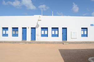 un edificio bianco con porte blu sopra di Apartamentos El Marinero - Iglesia a Caleta de Sebo