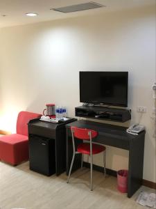 a room with a desk with a television and a chair at Big Bear Hotel in Kaohsiung