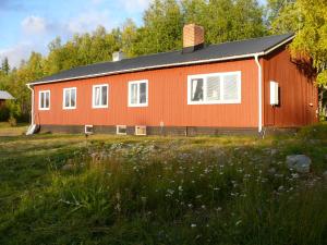 una casa rossa con finestre bianche in un campo di Stora Björnstugan a Laisvall