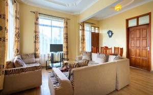 Sala de estar con 2 sofás y TV en Rayan Apartments & Safaris en Arusha