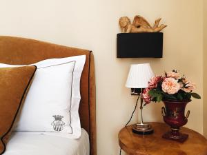 un lit avec un vase de fleurs sur une table avec une lampe dans l'établissement Casa Roma Luxury Apartment, à Rome