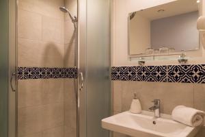 a bathroom with a shower, sink, and mirror at Hotel Memories Budapest in Budapest