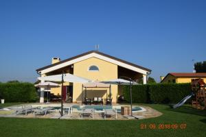 ein Haus mit einem Pool, Stühlen und Sonnenschirmen in der Unterkunft Villa Posta Vecchia in Loreo