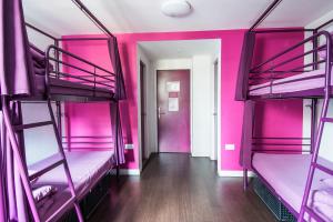 ロンドンにあるセーフステイ ロンドン エレファント & キャッスルのピンクの二段ベッドが備わる客室で、廊下があります。
