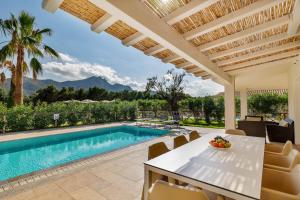 een villa met een zwembad en een tafel en stoelen bij Ville D'Ogliastra in Cardedu