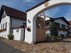 un edificio blanco con una puerta de madera en una calle en Hostinec Selský dvůr, en Zbiroh