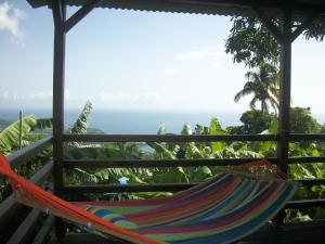 a hammock on a porch with a view of the ocean at mango tree lodge in Bouillante