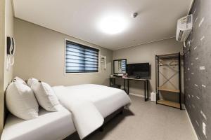 a bedroom with a white bed and a television at It's W in Suwon