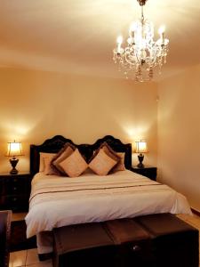 Un dormitorio con una cama grande con una lámpara de araña. en Kimberley Manor Guesthouse, en Kimberley