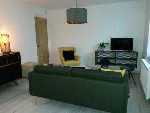 sala de estar con sofá verde y sillas en Pause Messines Chez Anne-Marie, en Verlinghem