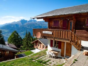 a wooden house with a balcony and mountains in the background at Chalet Saflischmannli auf der Alpe Rosswald in Rosswald