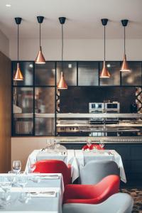 um restaurante com mesas brancas, cadeiras vermelhas e luzes em Hotel Berria em Hasparren