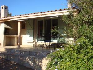a house with a porch with a table and chairs at Residence La Beloutiere in Porto-Vecchio