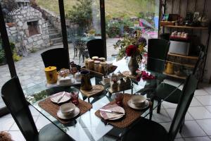 uma mesa de vidro com cadeiras e pratos em Les Tanneries em Villar-Saint-Pancrace