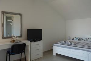 Apartments and Rooms Lux في سينج: غرفة نوم بسرير ومكتب مع تلفزيون