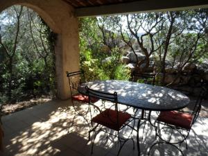 a patio with a table and chairs on a porch at Residence La Beloutiere in Porto-Vecchio