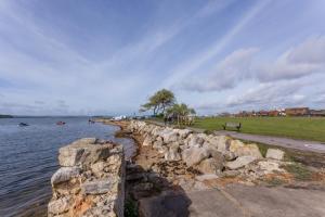 a stone retaining wall next to a body of water at Flutes in Poole