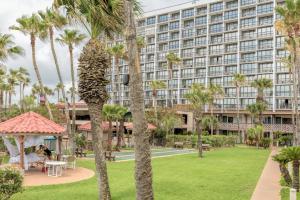 a large building with palm trees and a park at Isla Grand Beach Resort in South Padre Island