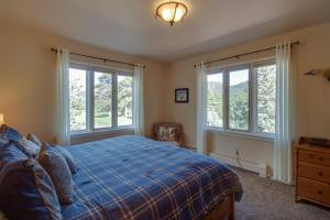 a bedroom with windows and a bed with a blue comforter at Cottage of Course - Permit #3092 in Estes Park