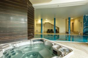 a bath tub in a bathroom with a swimming pool at Dziki Potok Konferencje Grill & Prestige SPA in Karpacz