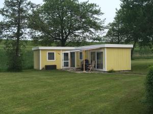 een klein geel huis midden in een tuin bij Beach Chalet am Wasser Nr. 169 in Andijk