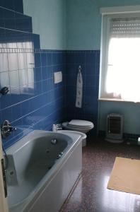 La salle de bains est pourvue de carrelage bleu, d'une baignoire et de toilettes. dans l'établissement Lella's sweet home, à Malo