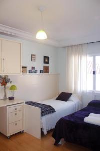 1 dormitorio con 2 camas, escritorio y ventana en FamilyHome, en Florianópolis