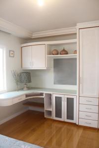 cocina blanca con armarios blancos y mesa en FamilyHome, en Florianópolis