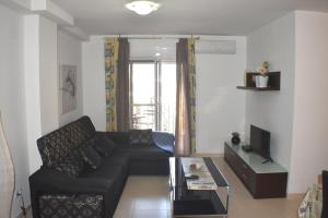 a living room with a black couch and a tv at Apartament Montse in Camarles