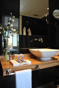 baño con lavabo y jarrón de flores en Hotel Sardinero Madrid, en Madrid