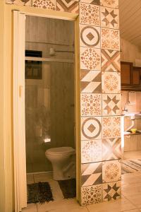 a bathroom with a toilet and a tiled wall at Trindade Hospeda - Casa 2 - 20 Passos da Areia in Trindade